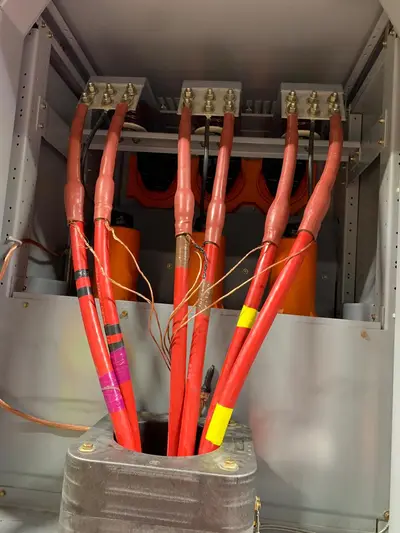 Six single-conductor medium-voltage cables entering a cubicle, stress cones dressed to a common height and the phase conductors carried up through standoff insulators.