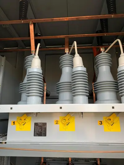Three vacuum switches on a pole-mounted capacitor control, each with an open and closed position placard, wired back to a common control cabinet.
