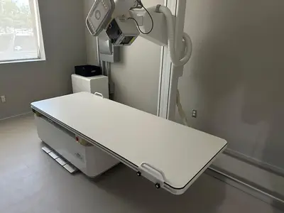 A radiographic room with the table in place and the equipment feed brought up in the corner behind it.