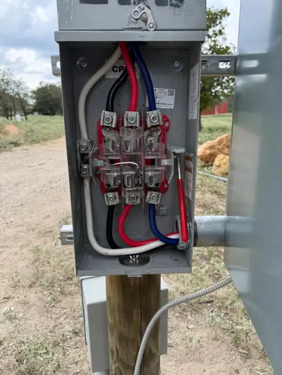 A pole-mounted meter enclosure opened up, service conductors landed on the line-side lugs and the manufacturer's data label on the inside face.