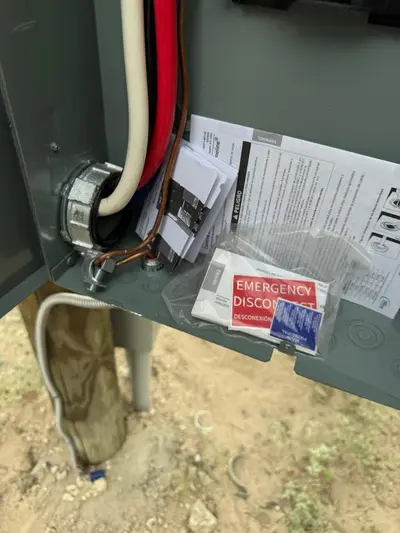 An emergency-disconnect placard fitted at the service equipment, with the load center alongside.